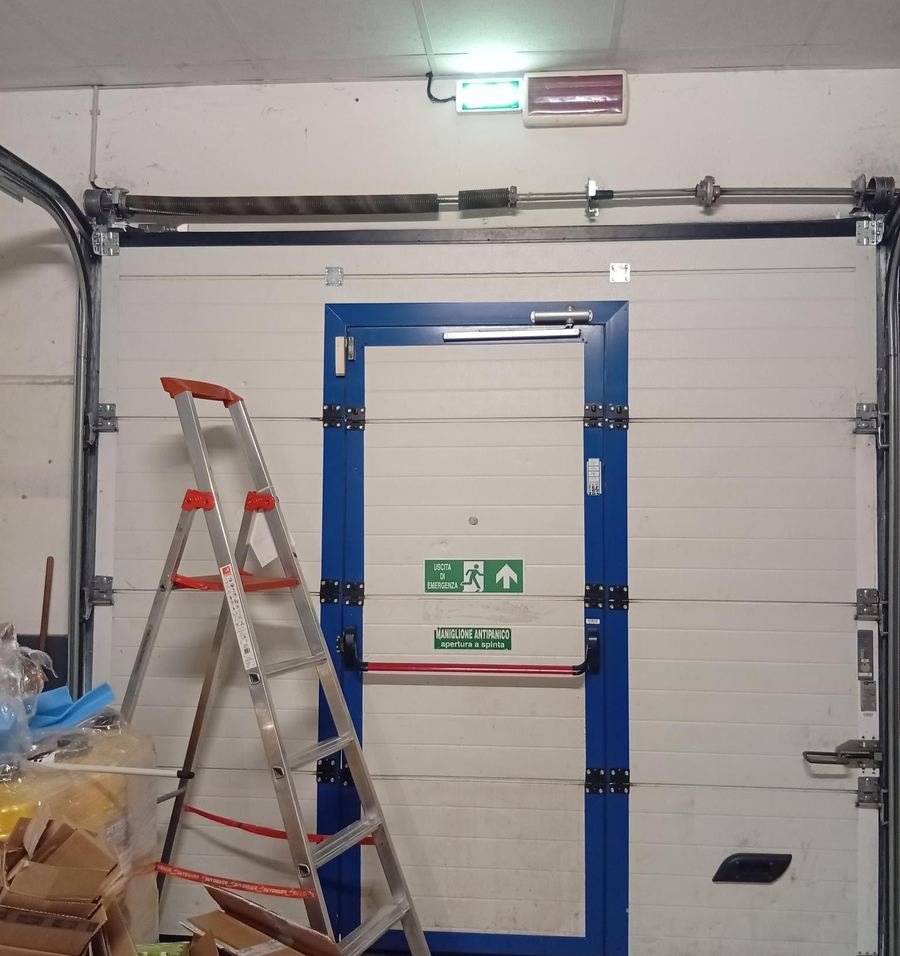 Portone sezionale di un magazzino con porta pedonale durante la manutenzione